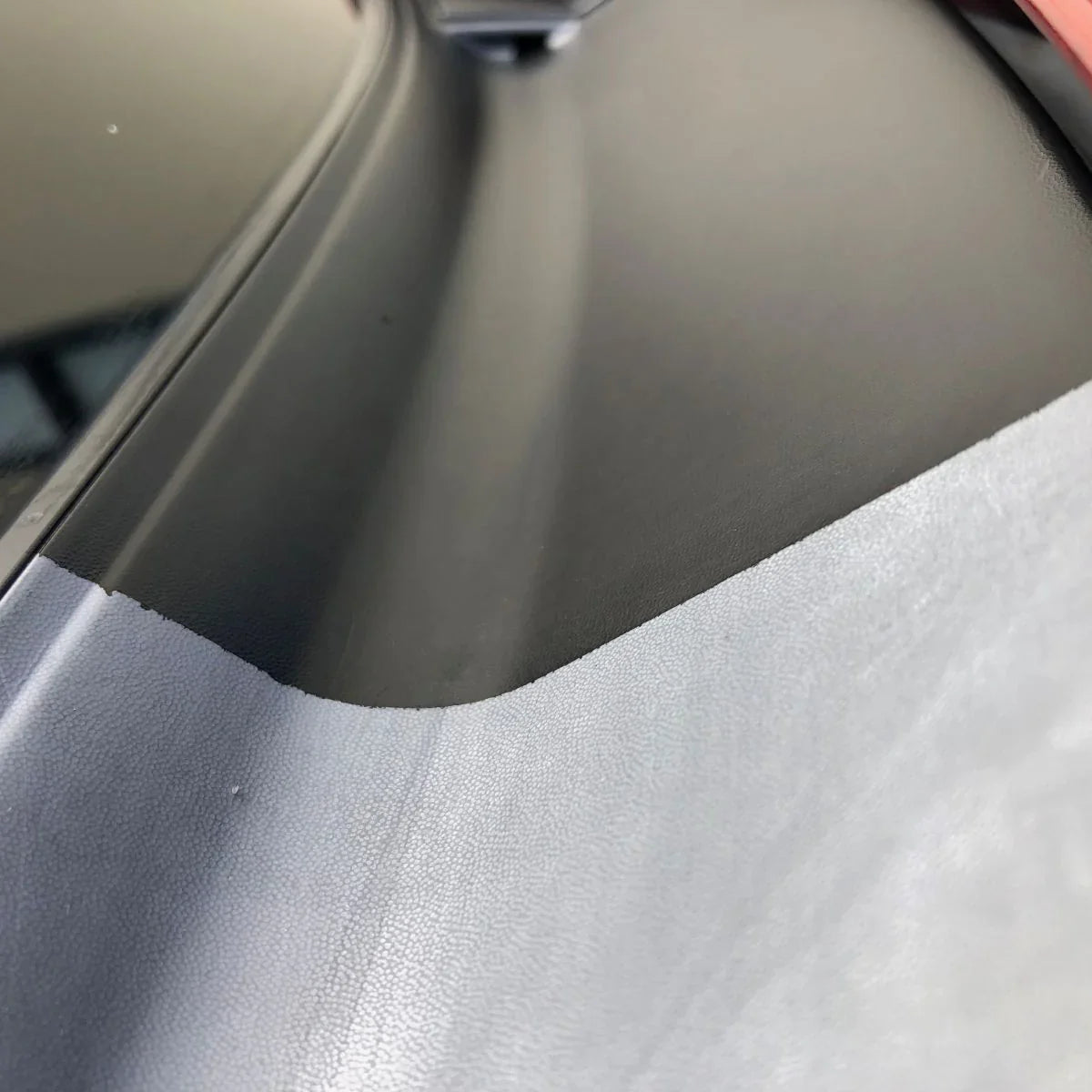 Close-up of restored black car trim surface treated with Ceratek ceramic coating.